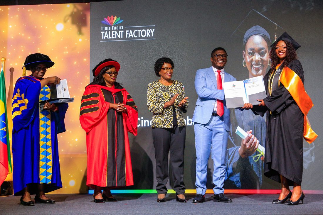 A certificate being handed over on stage to a robed recipient