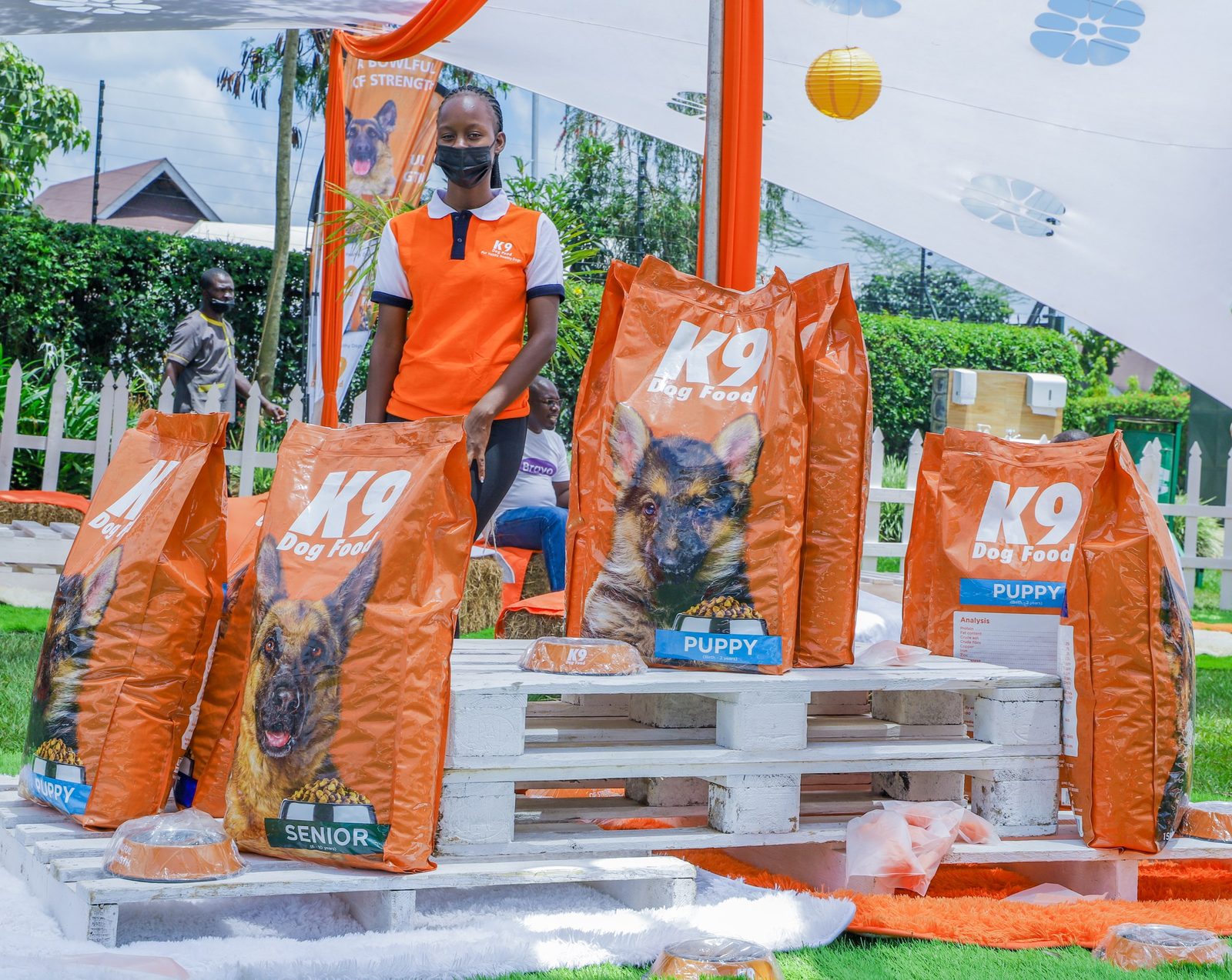 A pallet display stacked with K9 dog food packs under a stretch tent