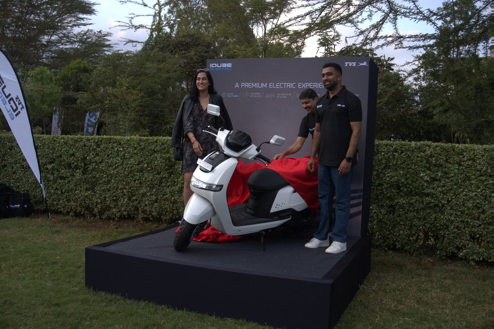 An electric scooter presented on a plinth with two hosts alongside