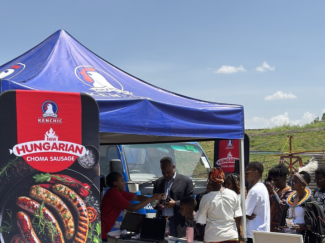 A Kenchic Choma Sausage totem with staff serving a queue of customers