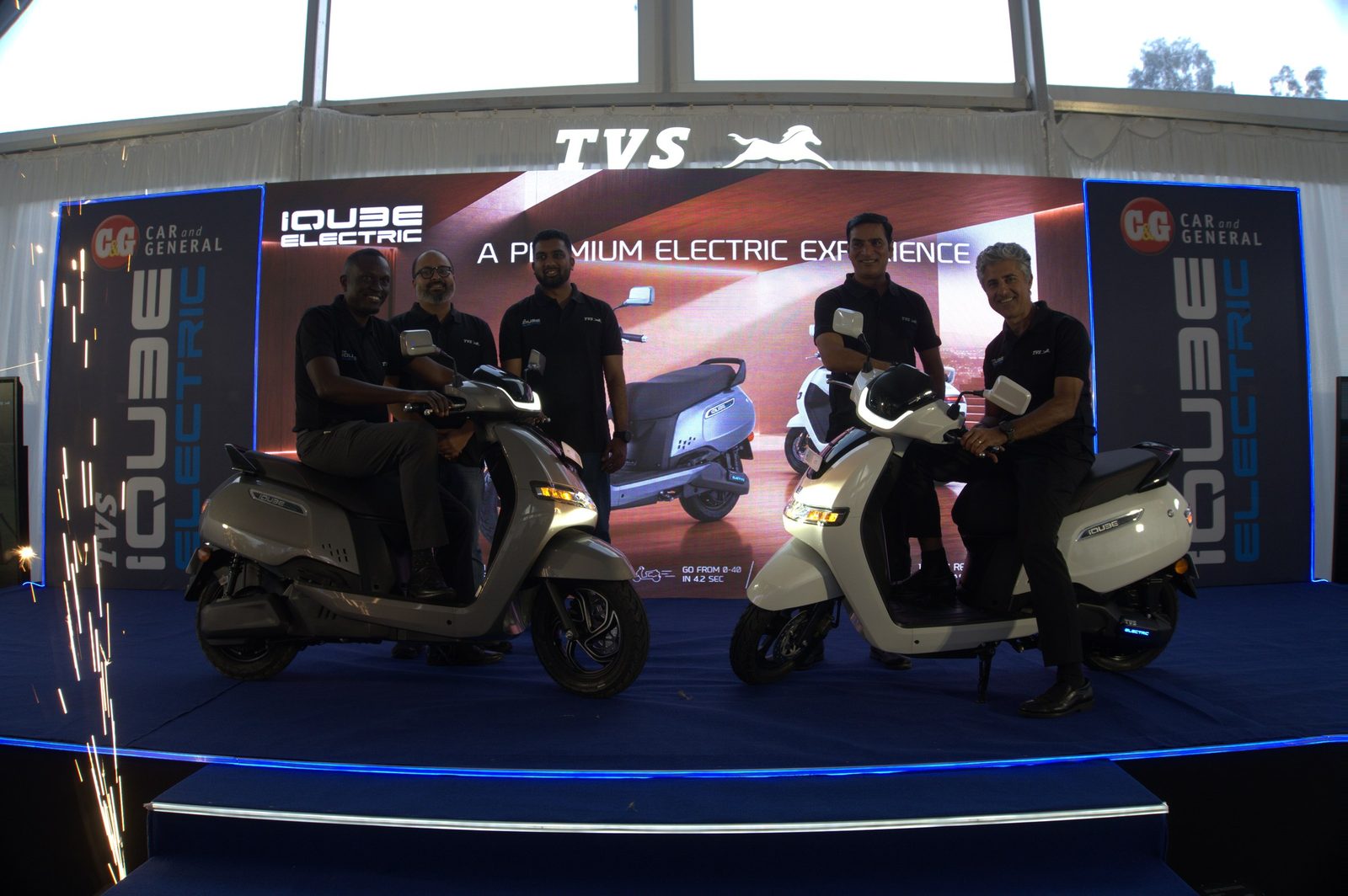 A product launch stage with an LED wall and an electric scooter presented under stage lighting
