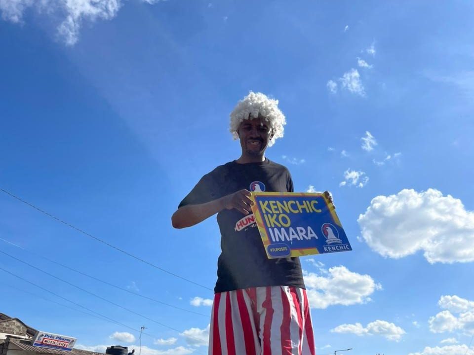 A stilt walker carrying a branded placard above street traffic
