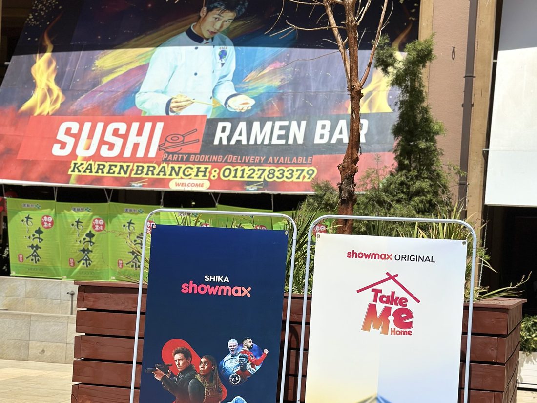 A printed brand totem standing in a covered walkway beside a food outlet