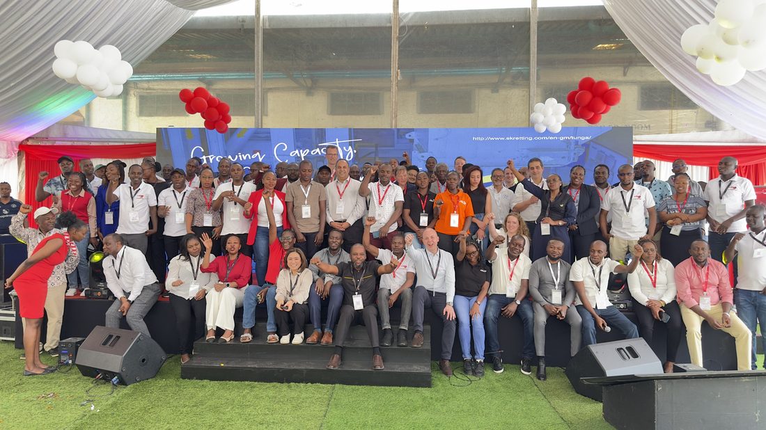 A large company group photographed together on tiered staging