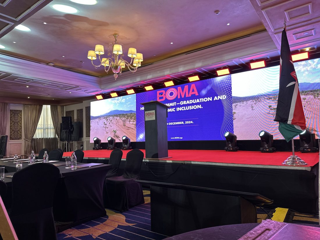 A ballroom laid with cabaret tables facing a full-width LED wall