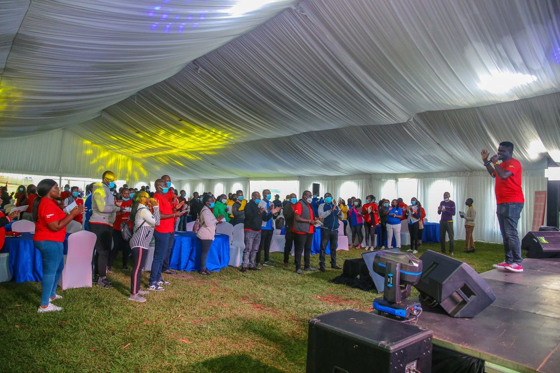 A standing crowd filling a marquee while an MC works the front of the room