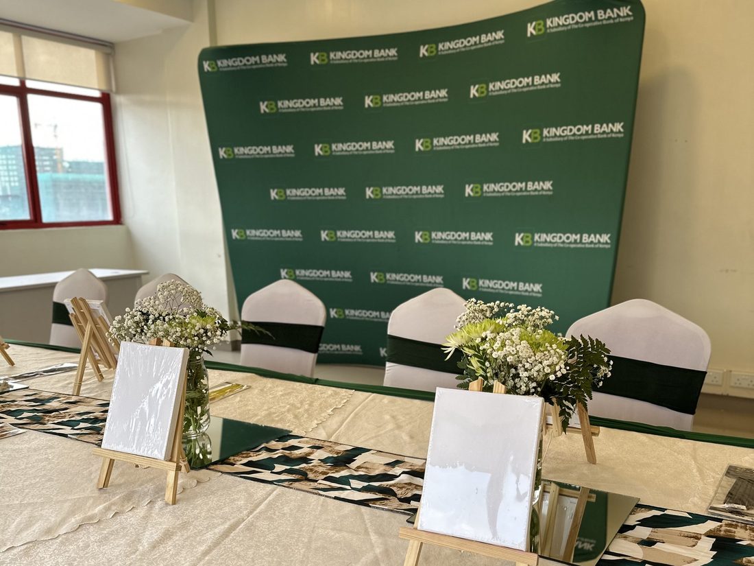 A dressed table with easels set in front of a printed Kingdom Bank backdrop