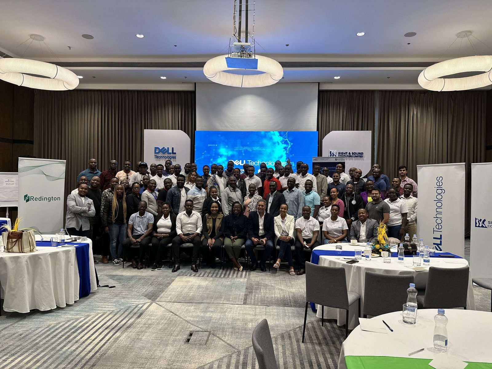 A room of delegates gathered in front of a branded presentation screen