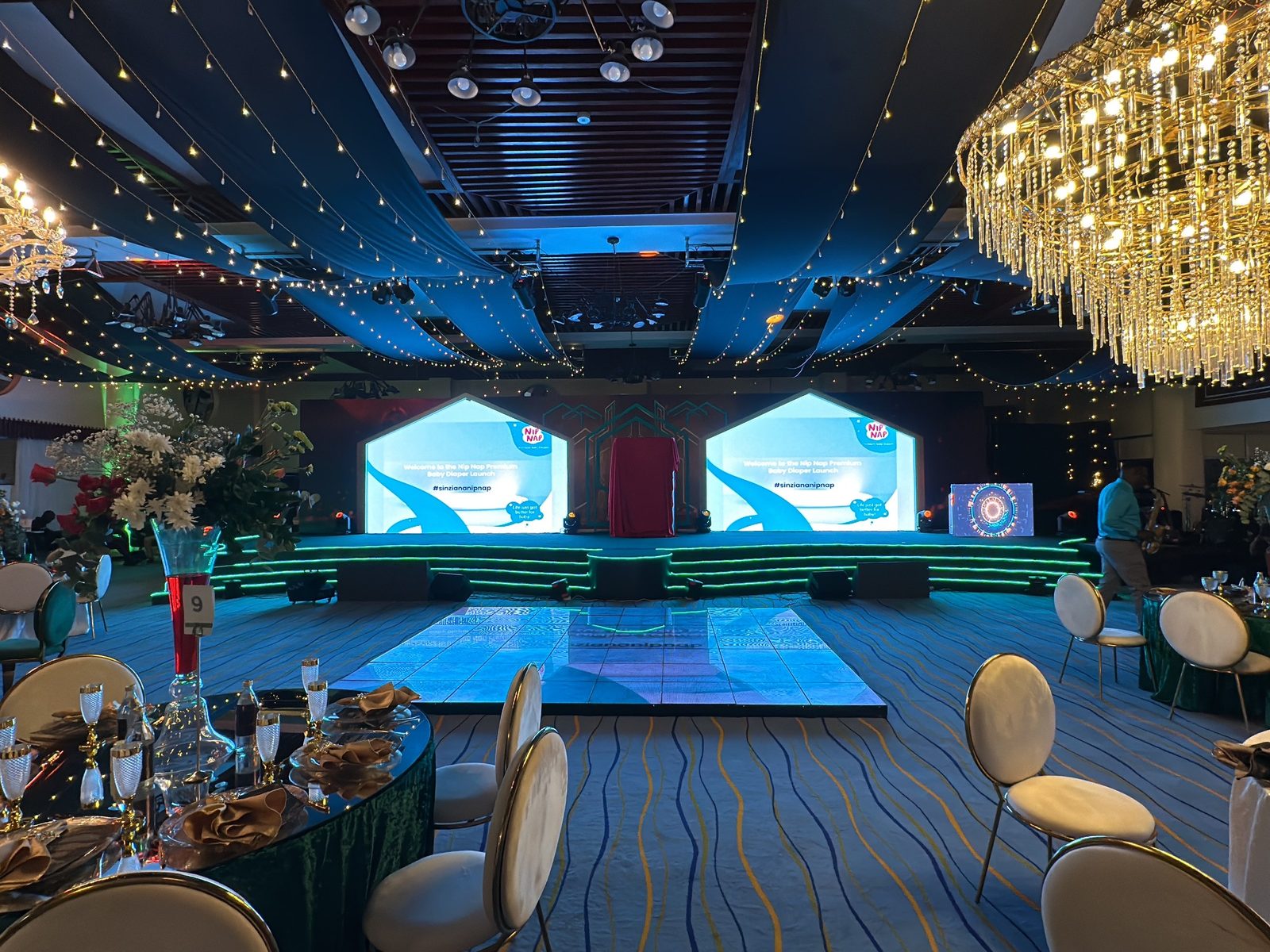 A ballroom dressed for a launch with twin LED screens, an arched reveal and a lit dance floor