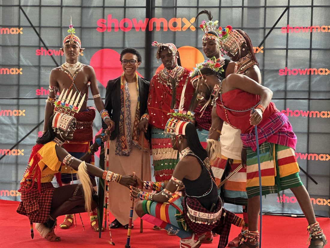 Traditional dancers performing around a laughing guest on an event carpet
