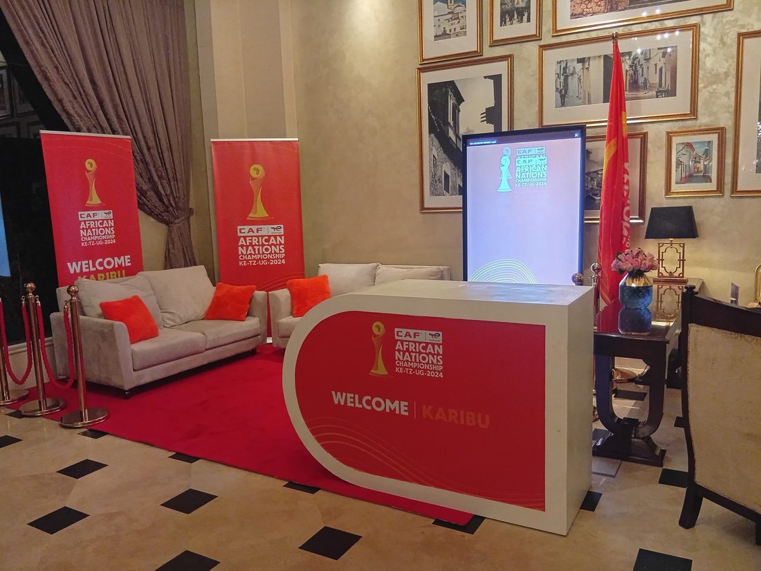 A tournament hospitality lounge with a red carpet, upholstered seating and a lit reception counter