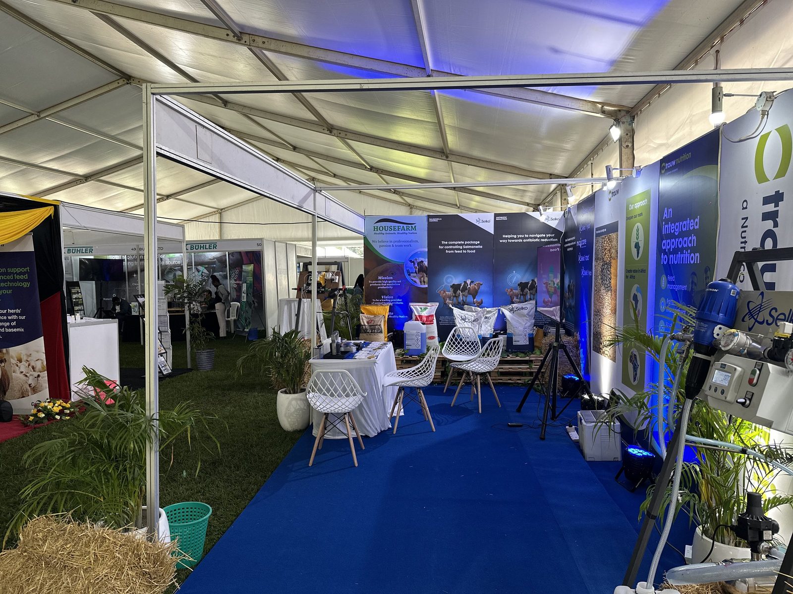 The interior of a marquee exhibition hall with a blue carpeted aisle and stands either side