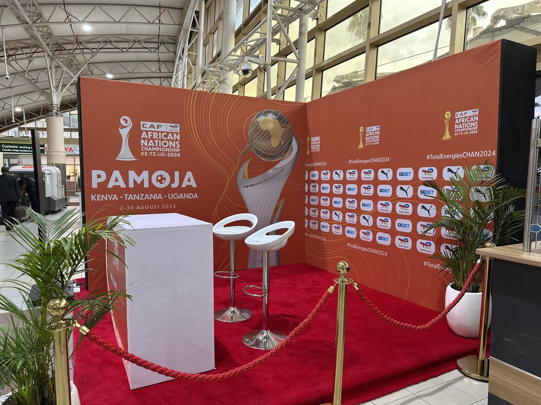 A branded welcome desk with bar stools in front of a printed wall