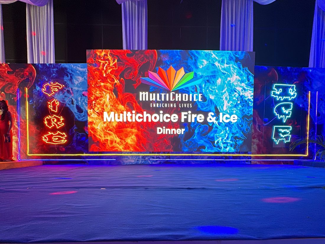 A lit dinner stage with a screen and an open dance floor in front of it
