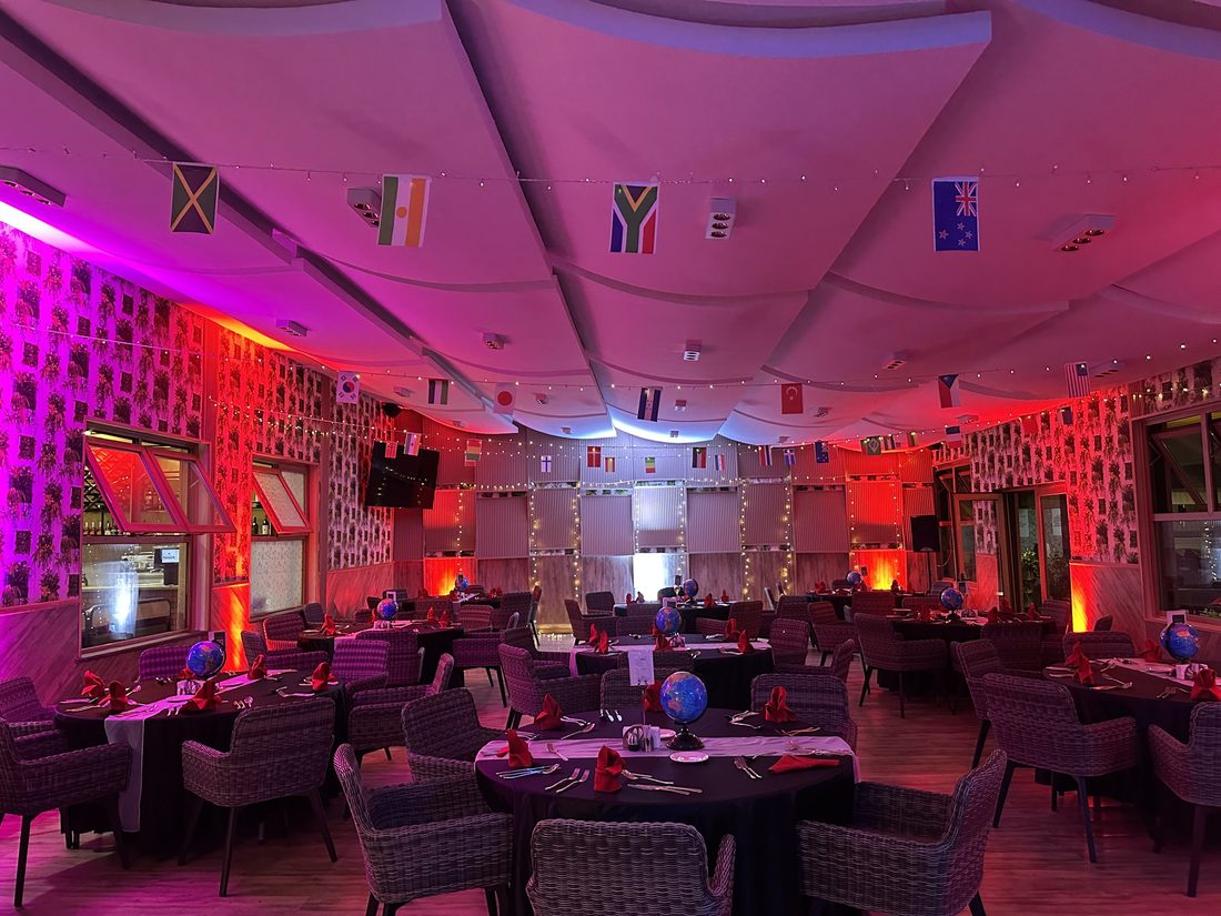 Dressed dinner tables in a room under deep pink and red uplighting