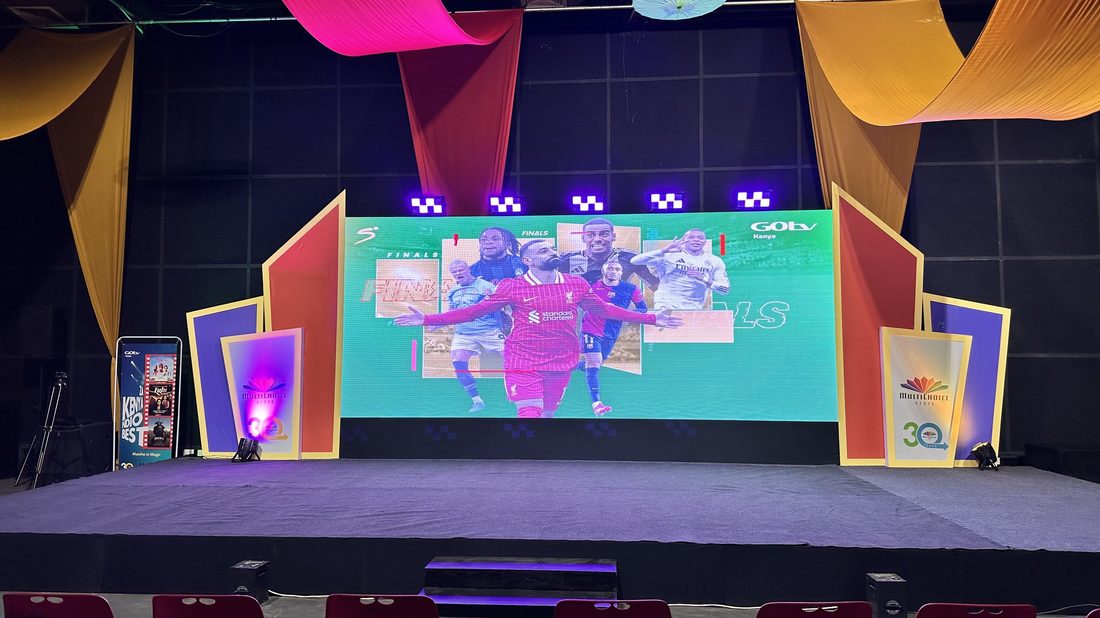 A stage framed by coloured drapes with an LED screen at its centre
