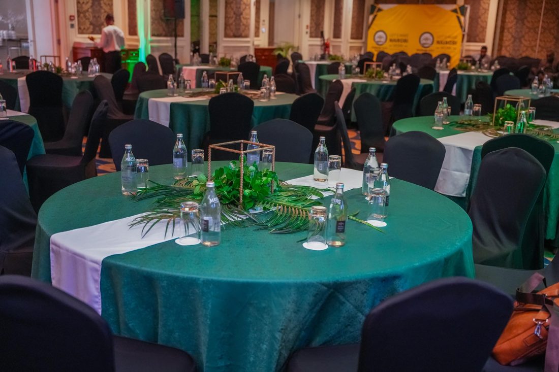 A banquet round dressed in green linen with a foliage centrepiece and place settings laid
