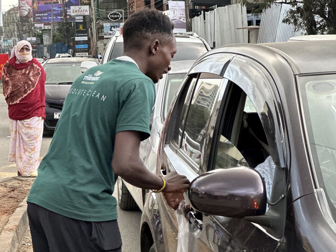 A field representative handing a sample through a car window in traffic