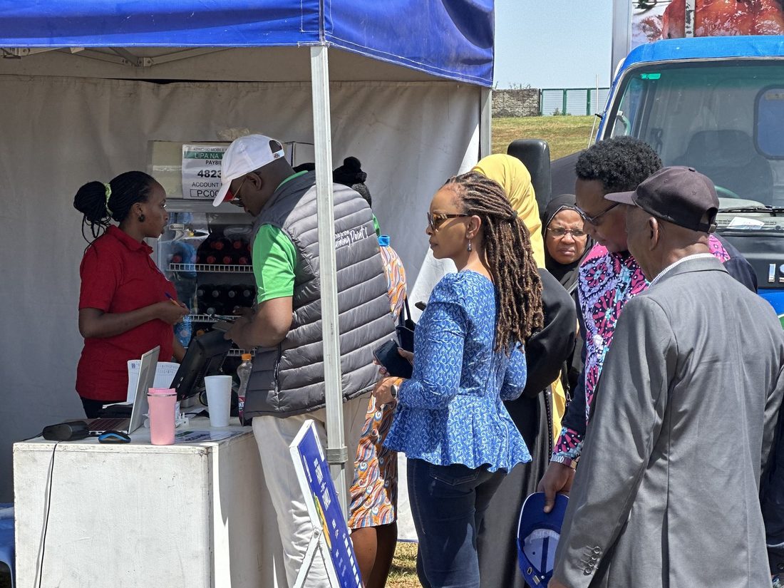 People queuing at a blue branded gazebo beside a mobile unit