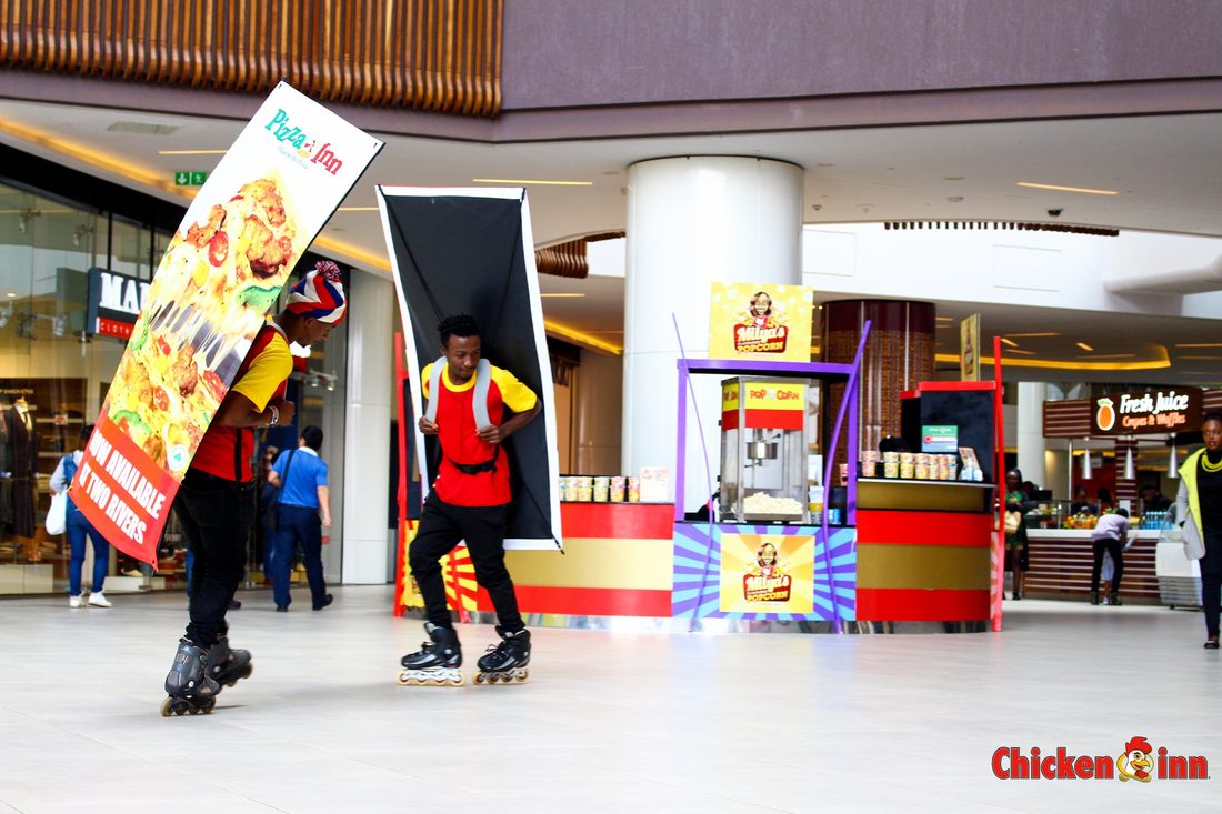 A distributor on rollerblades carrying printed placards through a shopping centre