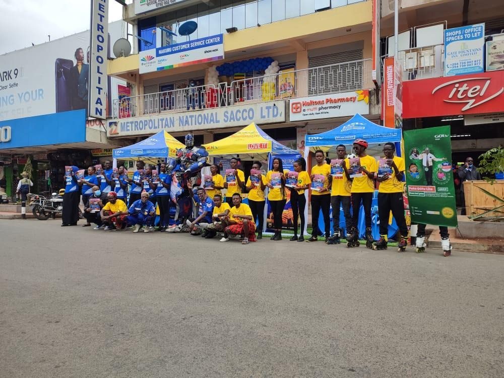 A large field team assembled on a street in front of a row of shops