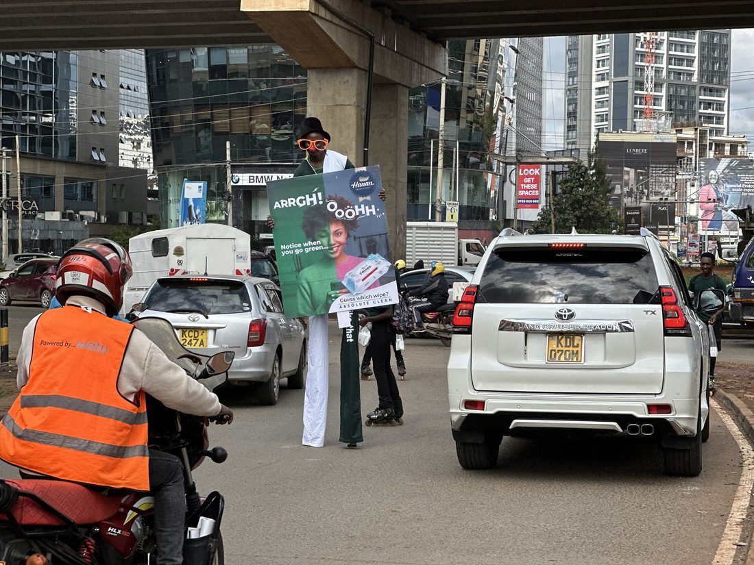 A street team distributing samples between cars at a junction