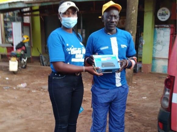 Two field representatives holding a product box between them on a street
