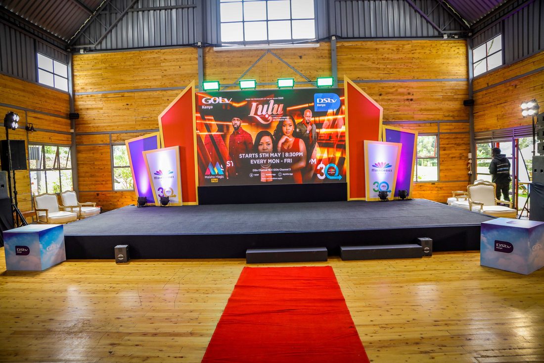 A launch stage with twin screens and a red carpet approach inside a timber hall