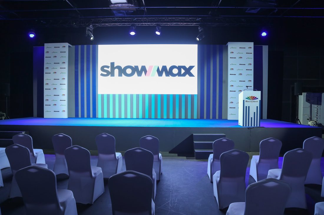 A Showmax stage set with a lit backdrop and tiered seating, photographed before the audience arrives