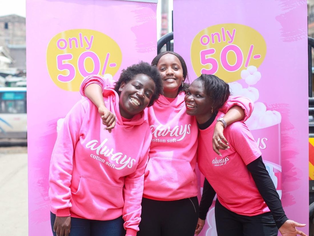 Three brand ambassadors in front of a pink branded backdrop