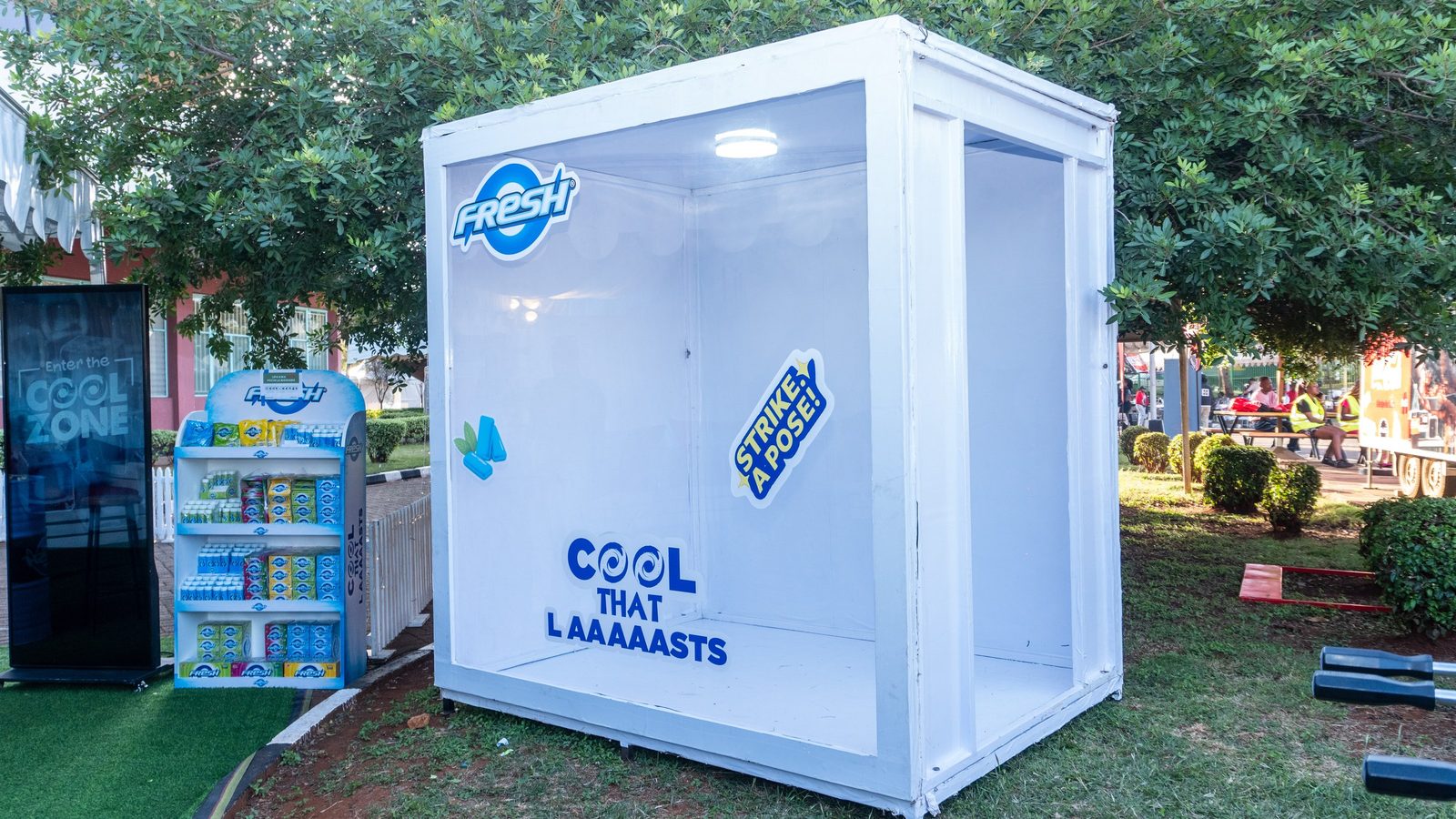 A Fresh Cool Zone photo cube beside a stocked product gondola on a lawn