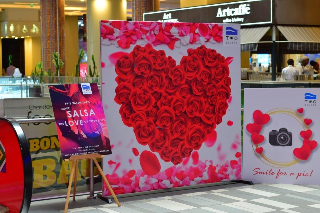 A rose-covered heart photo wall beside a branded photo unit