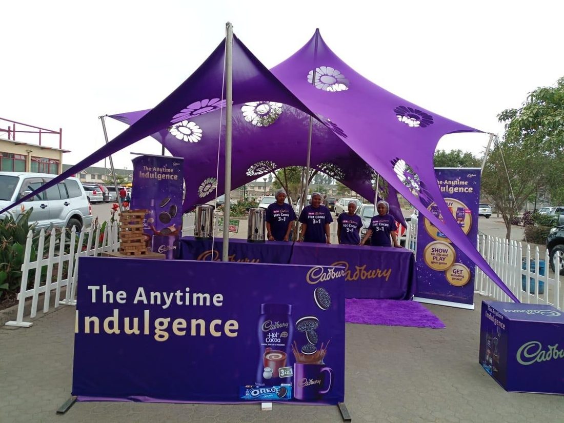 A purple stretch-tent activation build with branded signage and picket fencing