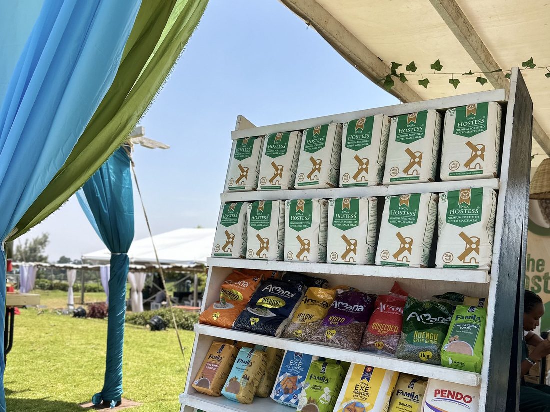 A tiered outdoor shelf merchandised with Unga product packs under a tent