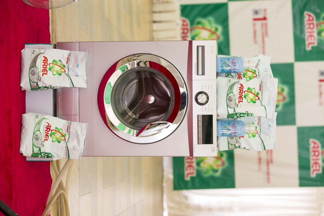 An Ariel demonstration unit built around a front-loading washing machine with packs arranged on the checkerboard surround
