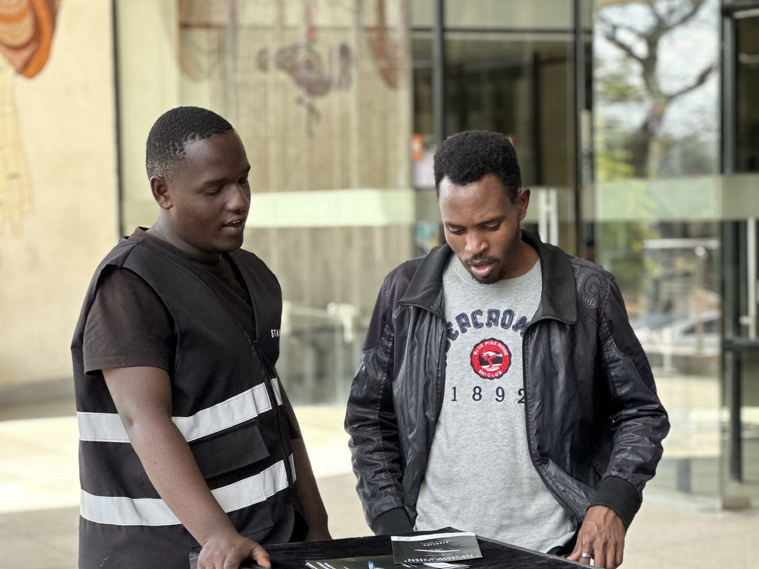 Two men looking at a Starlink display unit outside a building entrance