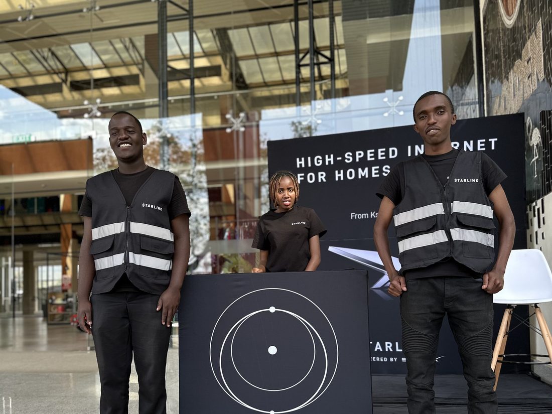 A Starlink display plinth in a shopping centre walkway with two security officers standing beside it