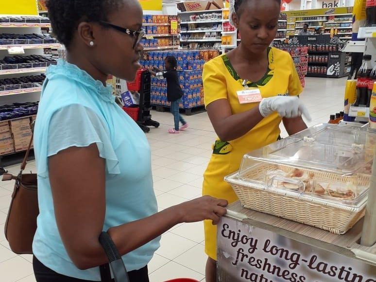 A shopper carrying a store basket being served at the display