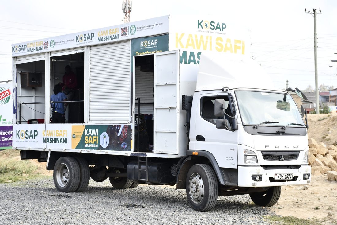 A branded roadshow truck with the stage bay open in hard daylight