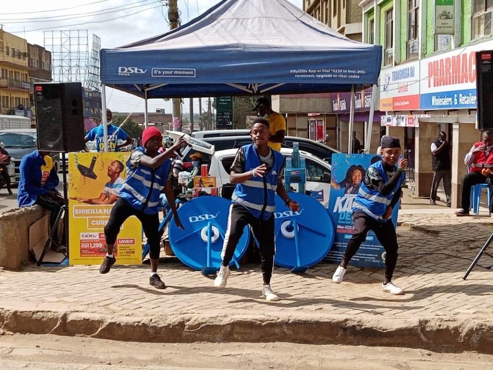 Dancers in blue performing in front of a branded stage on a street