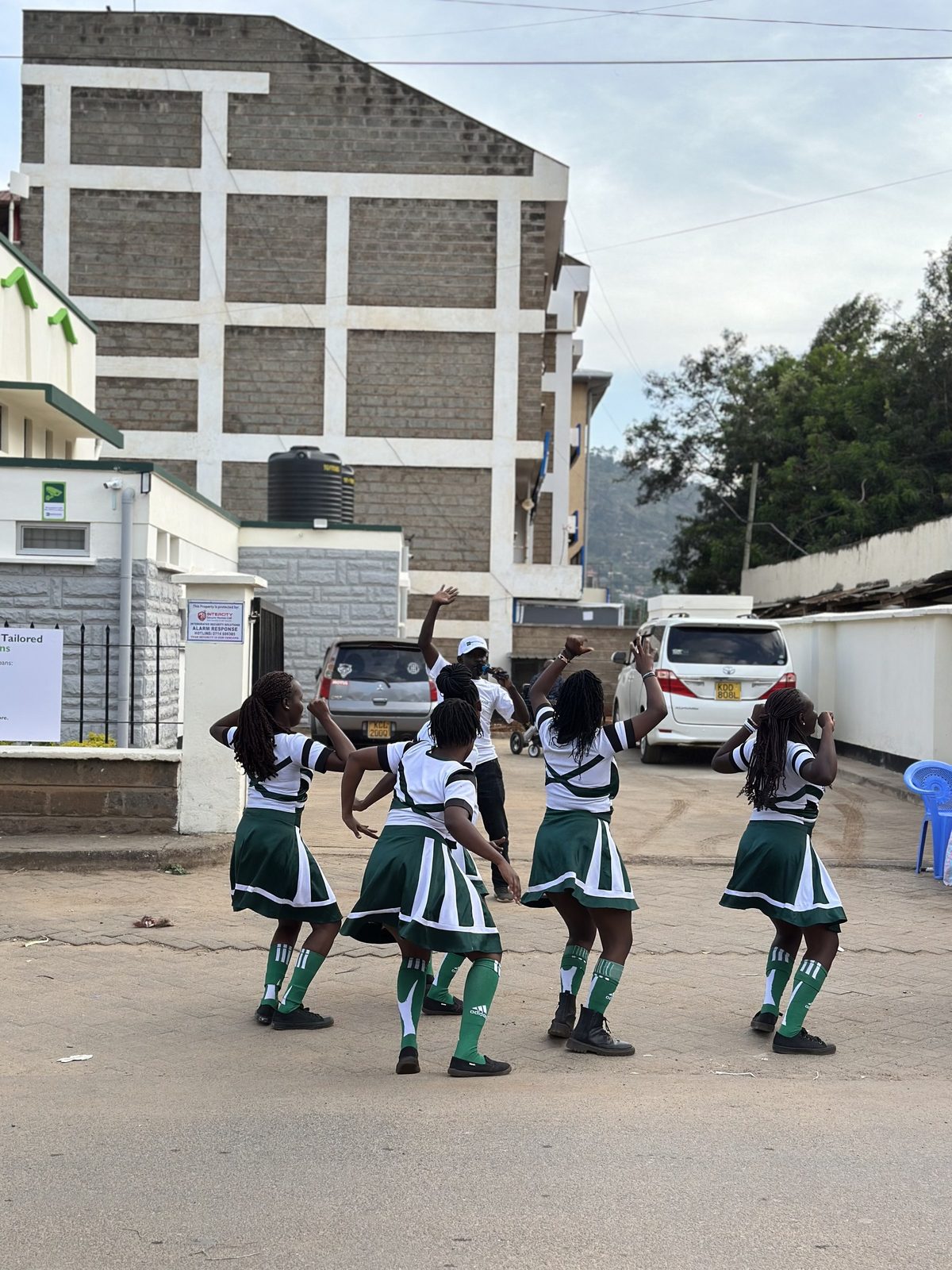 A dance troupe in matching kit performing a routine on a town street