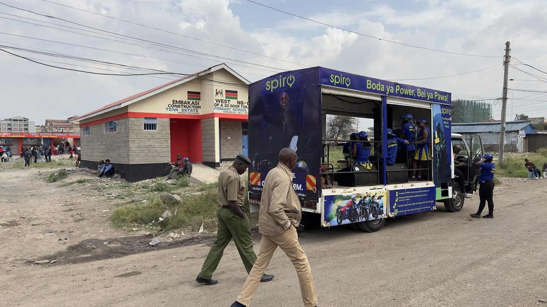 A branded route truck working a roadside trading centre, pedestrians passing in front of it