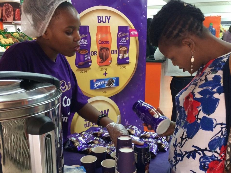 A promoter pouring a sample cup for a consumer