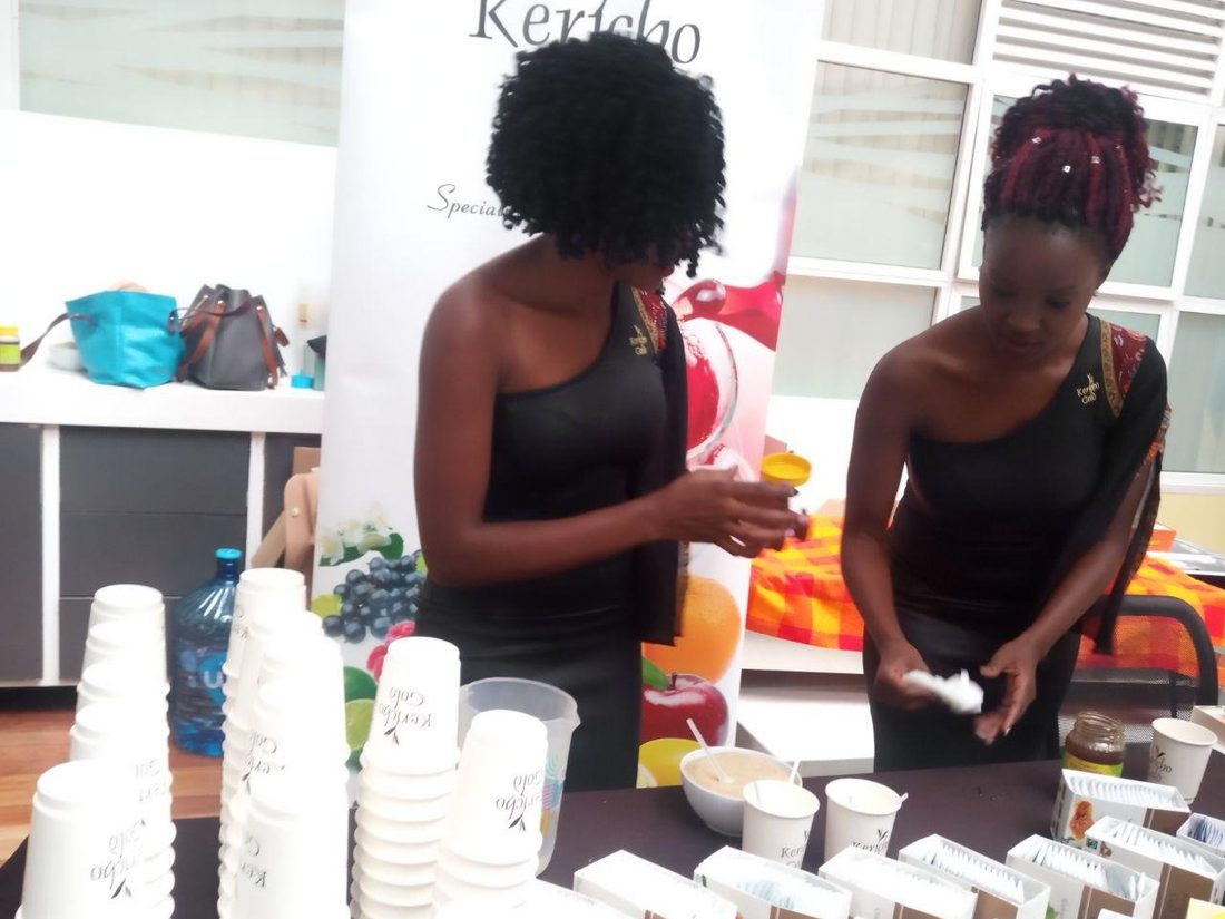 Two hostesses making up tea samples at a Kericho Gold table