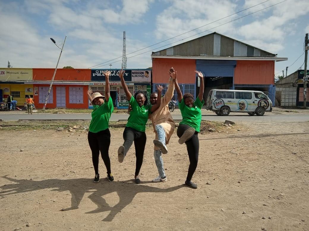 Three crew members jumping together on a street in matching kit