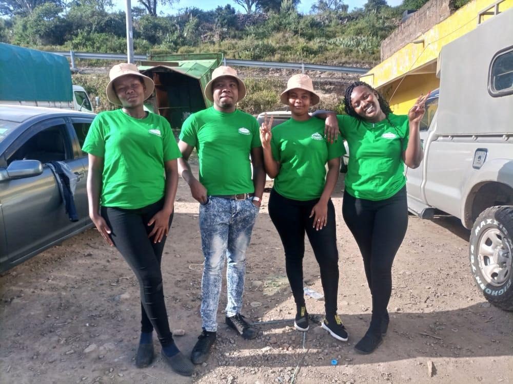 Four crew in matching green tee shirts beside a branded vehicle