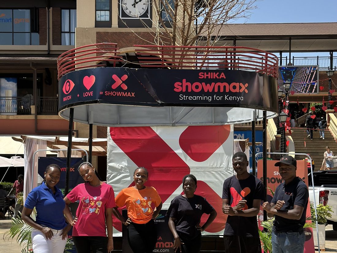 A team lined up in front of a Showmax installation in a plaza