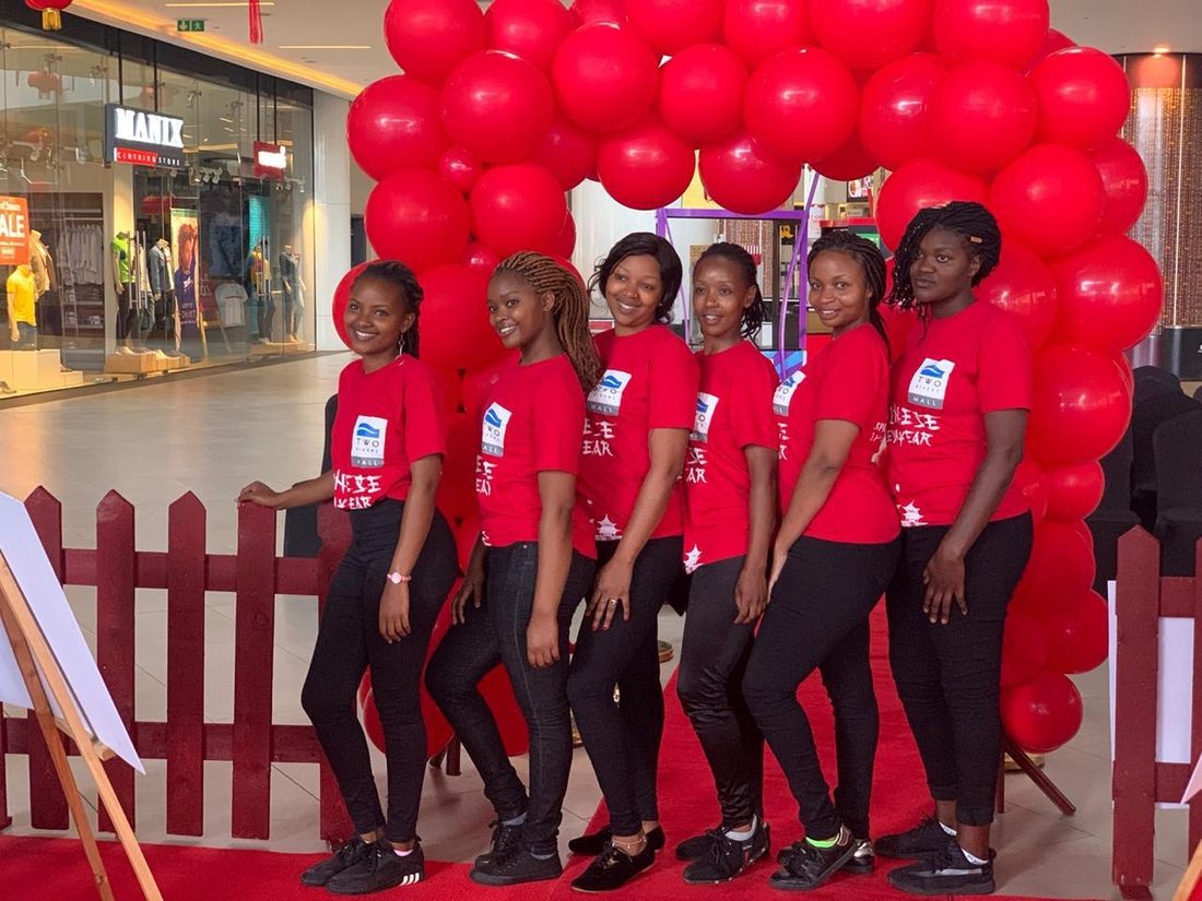 A team in red shirts at a shopping-centre balloon arch