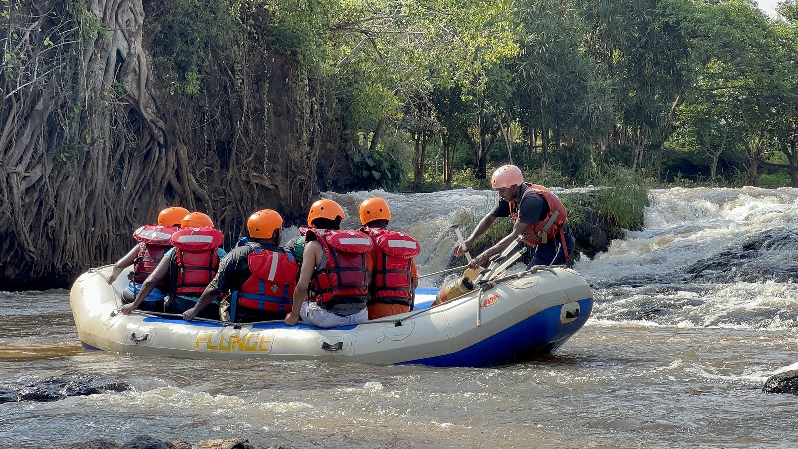 A rafting crew running a rapid together in full safety kit