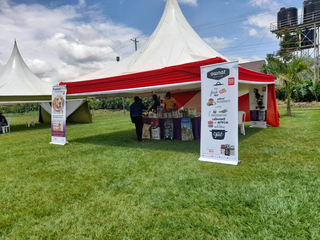 A red and white gazebo with printed banners on a lawn